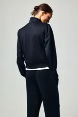 Campera deportiva corta de punto grueso con leve brillo, cuello elevado, cierre frontal y bolsillos laterales insertados.