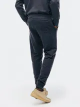 Pantalón tipo babucha de color azul oscuro, confeccionado con interior de felpa. Presenta cintura elástica con cordón de ajuste y puños acanalados en los tobillos.