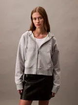 Buzo gris con capucha, cierre frontal con cremallera, logo de Calvin Klein bordado en el pecho y corte cropped.