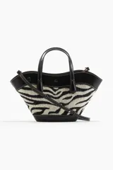 Cartera tipo tote con diseño de estampado animal print de cebra, confeccionada en tejido jacquard con detalles en material sintético negro. Cuenta con doble asa de mano, correa larga ajustable y extraíble para usar como bandolera, y cierre interno de mosquetón.