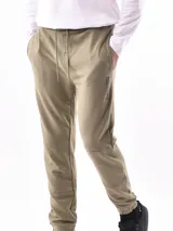 Pantalón de jogging negro, de corte ajustado con puños elásticos en los tobillos y cordón de ajuste en la cintura. Presenta paneles superpuestos en las rodillas y un pequeño texto vertical estampado en la pierna derecha.