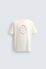 Camiseta de corte regular, color crudo, con cuello redondo y manga corta. Presenta un estampado frontal con diseño circular en tono rojizo con efecto lavado.