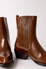 Bota de cuero negro estilo texano, con caña media, elástico lateral con costuras verticales y taco cuadrado.