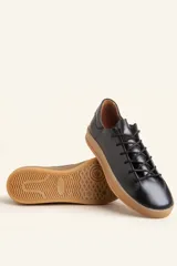 Zapatilla de cuero vacuno color azul marino, con cordones azules y suela de caucho color caramelo.