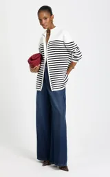 Cardigan de punto Le lis Blanc, color blanco con rayas horizontales negras, cuello alto con cierre frontal y mangas largas.