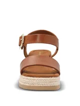 Sandalias Hush Puppies modelo Lili, color marrón, con plataforma de yute y suela de caucho. Presentan una tira ancha en el empeine y una correa ajustable al tobillo con hebilla metálica dorada.