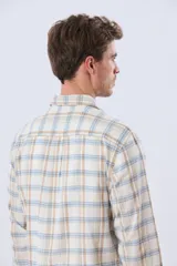 Camisa de manga larga de lino y algodón, con estampado a cuadros en tonos beige, blanco y celeste, cuello camisero y cierre frontal con botones.