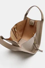Bolso bandolera de formato city en color gris topo, con pespuntes decorativos, doble asa de mano, cremalleras laterales y cierre imantado.