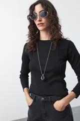 Remera de manga larga negra, de calce entallado, con cuello a la base y costuras verticales que estilizan la silueta.