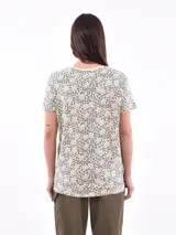 Remera de mangas cortas con estampado de flores abstractas en tonos azul y lila sobre fondo blanco.