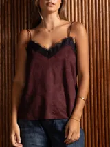 Top estilo camisola de textura símil gamuza en color bordó, con breteles finos y detalle de encaje negro en el escote. Presenta una costura vertical en el centro del frente.