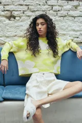 Bermuda de lino color arena, con diseño de tiro alto, pinzas frontales y cierre con botón personalizado.