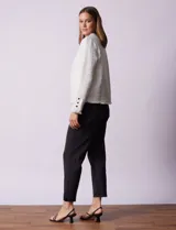 Chaqueta de tejido tweed color blanco con destellos brillantes, de corte recto y estructurado. Presenta cuello a la base, abertura frontal y puños decorados con botones en contraste. Los bordes del cuello, la cartera frontal y el ruedo cuentan con una terminación deshilachada.