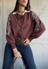 Sweater de punto color chocolate con cuello redondo y mangas largas abullonadas. Presenta detalles bordados con lentejuelas brillantes en los hombros y parte superior de las mangas.