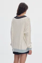 Sweater de punto oversized de color marrón, con escote en V, detalles de ochos y puños, cuello y ruedo en tono celeste y blanco.