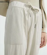 Pantalón jogger Marfinno color beige, confeccionado en suedine con cintura elástica y cordón ajustable. Presenta detalles perforados en los bolsillos laterales y en las costuras laterales, además de puños elásticos en los tobillos.