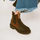 Botas estilo Chelsea de cuero color marrón, con paneles elásticos laterales negros, presillas traseras y suela chunky de goma negra con plataforma dentada.