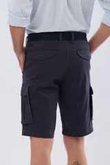 Bermuda cargo color azul marino, de gabardina con bolsillos laterales con solapa en las piernas y presillas para cinturón. Incluye cinturón de lona trenzada oscura con detalles en cuero sintético y hebilla metálica.