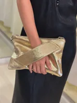 Sobre/cartera de cuero color dorado brillante, con diseño acolchado en la solapa. Incluye una correa larga para usar al hombro o como bandolera, y una correa corta para la muñeca. Ambas correas son desmontables.