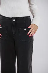 Pantalón de jean negro gastado, de corte recto, con bolsillos delanteros y sin trabillas.