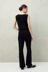 Pantalón blanco de tejido de punto, corte ancho y fluido, con botones dorados decorativos en la costura lateral exterior de ambas piernas.