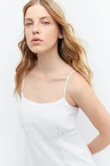 Vestido corto blanco de lino con breteles finos, corte recto y volado en el ruedo.