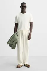 Sandalia color beige fabricada en piel con acabado serraje. Cuenta con dos tiras anchas ajustables mediante cierres adherentes y plantilla con horma anatómica.