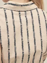 Vestido camisero corto confeccionado en tejido seersucker de algodón a rayas verticales azul marino sobre blanco, con cuello camisero, botones nacarados y lazo para ajustar la cintura con terminación en cobre.