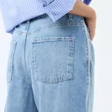 Pantalón de jean estilo baggy con tiro bajo, corte amplio y pierna recta. Presenta un lavado azul medio con costuras laterales destacadas en tono claro.
