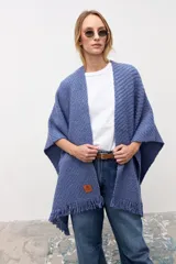 Ruana de tejido de punto con textura, color azul, con terminaciones de flecos en los bordes. Diseño envolvente y holgado.