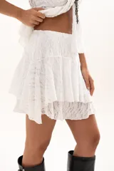 Pollera corta de encaje blanco con diseño de volados escalonados y cintura elástica.