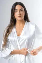 Bata corta color blanco de satén elastizado, con mangas tres cuartos con volados y lazo para atar en la cintura.