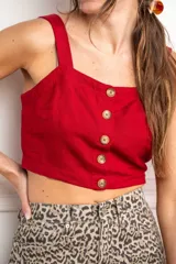 Top corto color rojo, con escote cuadrado y tirantes anchos. Presenta una hilera de botones marrones en el centro del frente.