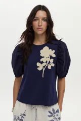 Blusa azul marino de algodón, con mangas abullonadas cortas de tela plana y gran bordado de rosa en tono crudo en el pecho.