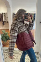 Campera de diseño combinado con cuello alto y cierre frontal. La parte superior presenta un estampado a cuadros en tonos beige y marrón, mientras que la parte inferior es de color verde oliva con un diseño acolchado en forma de rombos.