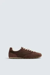 Zapatilla de estilo retro con cordones, confeccionada en una combinación de piezas de tela y cuero con acabado de gamuza. Cuenta con suela dentada en contraste.