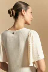 Remera de rib color beige, con cuello redondo y mangas cortas amplias con leve frunce en los hombros. Confeccionada en tejido elastizado de textura acanalada.