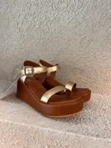 Sandalias de plataforma corrida color marrón con tira delantera simple, tira en el empeine y tira al tobillo con hebilla metálica.