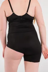 Calza modeladora negra reforzada en zona abdominal, tiro alto y corte a media pierna en la pierna derecha.