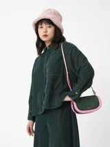 Camisa corta negra de terciopelo, de silueta cuadrada oversized, con bolsillo delantero y detalle en los puños y cuello con botón oro en forma de flor.