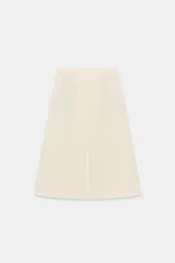 Falda de tiro medio color crema, con pliegue central en el delantero y bolsillo de vivo con botón en la parte trasera. Corte evasé.