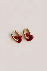 Aros tipo argolla pequeña de metal dorado con dije colgante en forma de corazón esmaltado en color rojo.