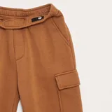 Pantalón de chándal color tostado, con cintura elástica, bolsillos laterales tipo cargo con solapa y puños elásticos en los tobillos.