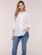 Camisa Magaschoni de silueta holgada y tejido texturizado color blanco, con cuello camisero, cierre frontal de botones, mangas largas con presilla para arremangar y diseño asimétrico con espalda más larga.