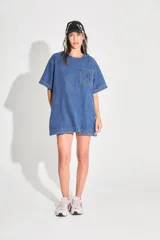Vestido corto de denim azul con corte holgado, mangas cortas y bolsillo frontal con logo bordado. Cuenta con cierre metálico en la espalda.