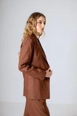 Blazer color crema con solapas de muesca, cierre frontal con dos botones y mangas largas con puños abotonados.