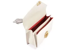 Mini bolso de mano Schutz modelo Brera, color blanco con textura granulada, solapa frontal con cierre metálico dorado y plateado, asa superior decorada con pañuelo estampado y correa ajustable para llevar al hombro o cruzado.