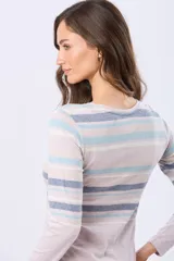 Remera de manga larga con cuello redondo y cierre frontal parcial con botones. Presenta un diseño de rayas horizontales en tonos pastel en la parte superior y un detalle de abertura lateral en el ruedo.