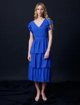 Vestido blanco de gasa con capas, marca Julia Jordan. Escote en V, manga corta con volados, corte en cintura y abertura central en espalda con cierre invisible.