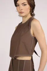 Blusa crop top negra sin mangas con cuello redondo y pespuntes blancos contrastantes.
